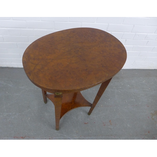 277 - A walnut veneered oval table, gilt roundels and tapering legs with an undertier, 55 x 73 x 40cm.