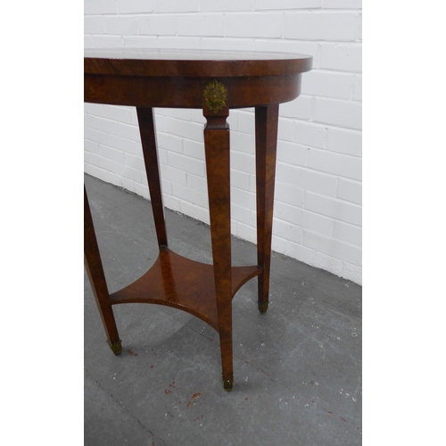 277 - A walnut veneered oval table, gilt roundels and tapering legs with an undertier, 55 x 73 x 40cm.