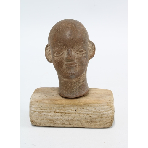 421 - Small pottery Buddha head, on a wooden plinth, 11cm high overall