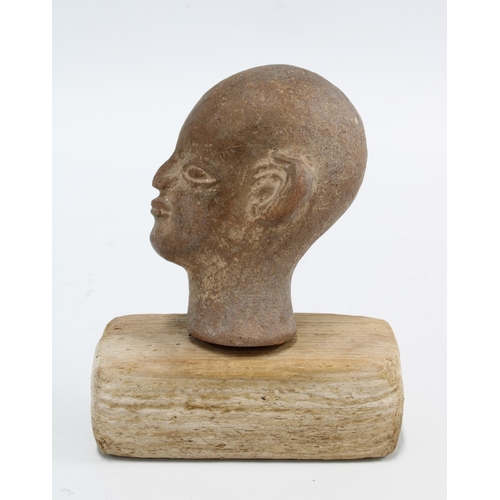 421 - Small pottery Buddha head, on a wooden plinth, 11cm high overall