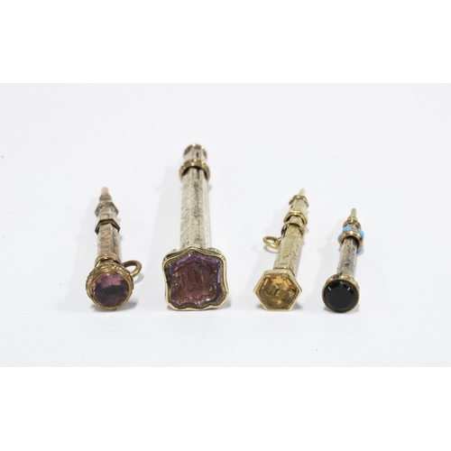 66 - Four Victorian yellow metal propelling pencils, each with a coloured hardstone terminal, two with in... 