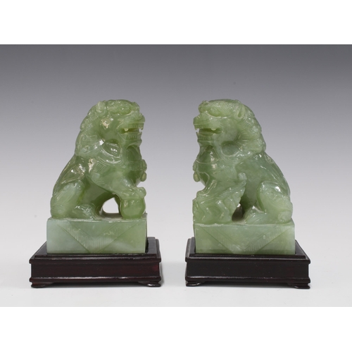 142 - A pair of carved jadeite temple lions on wooden bases (2) 15 x 10cm.