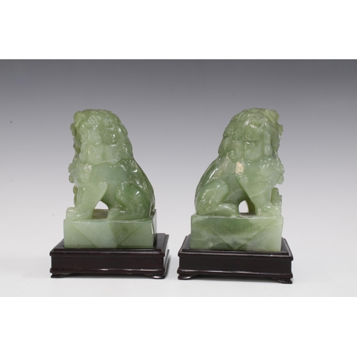 142 - A pair of carved jadeite temple lions on wooden bases (2) 15 x 10cm.