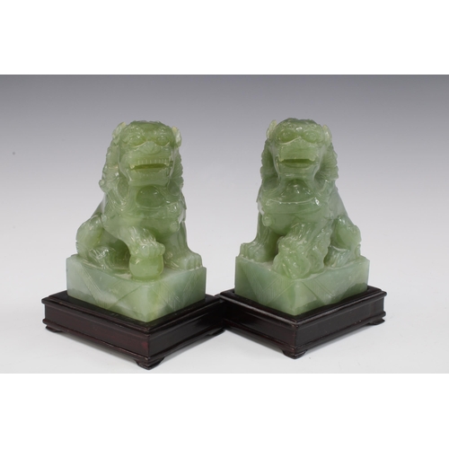 142 - A pair of carved jadeite temple lions on wooden bases (2) 15 x 10cm.