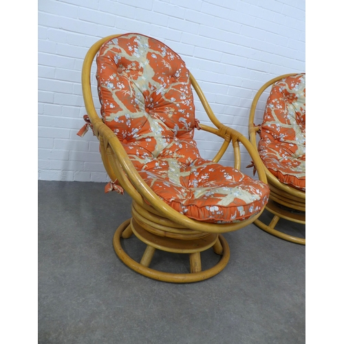 276 - Pair of retro bamboo revolving swivel  chairs, with loose orange pattern cushions, 76 x 98 x 60cm. (... 