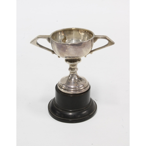 34 - Small silver trophy cup, on ebonised plinth, circa early 20th century, 10cm high overall