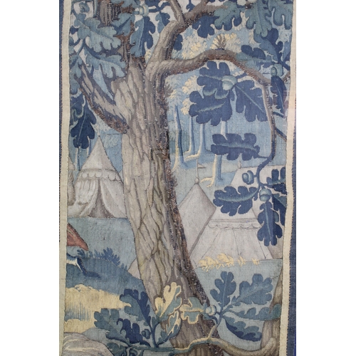 404 - An Antique tapestry showing a camp in a forest, framed under glass, 112 x 60cm