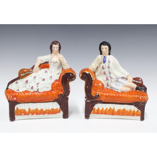 107 - A pair of 19th century Staffordshire musician figures, each modelled reclining on a chaise longue, 2... 