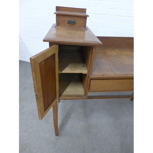 236 - An Arts & Crafts oak dressing table, ledgeback , flanked by a jewel drawer and cupboard, raised on s... 