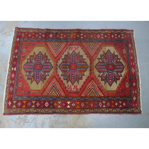 404 - Kazak style rug, red field with three flowerhead medallions, 192 x 132cm.