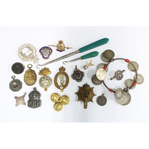 17 - A collection of military cap badges and buttons, a coin bracelet and button hooks, etc