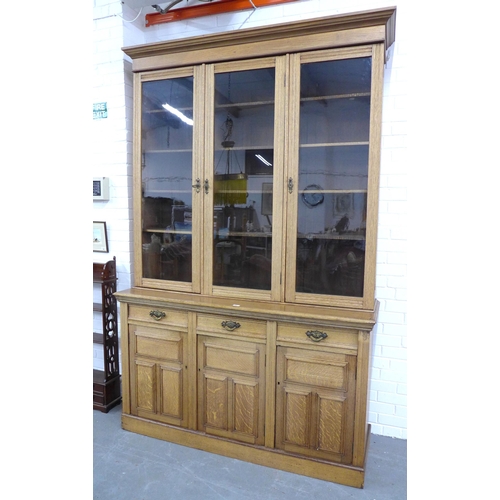 290 - An oak bookcase cabinet, projecting cornice above three glazed doors with a shelved interior, over t... 