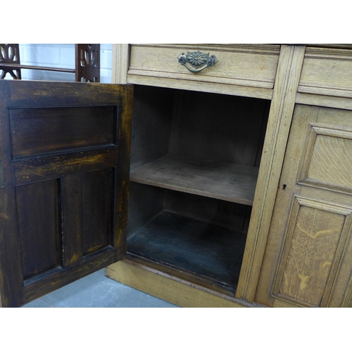 290 - An oak bookcase cabinet, projecting cornice above three glazed doors with a shelved interior, over t... 