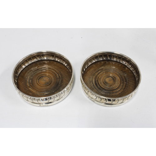 1 - A pair of silver wine coasters, London 1963, with wooden bases, 13cm diameter, together with a pair ... 