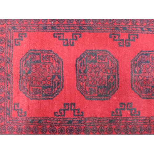 251 - Afghan rug, red field with four guls,  140 x 76cm.