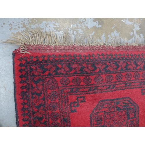 251 - Afghan rug, red field with four guls,  140 x 76cm.