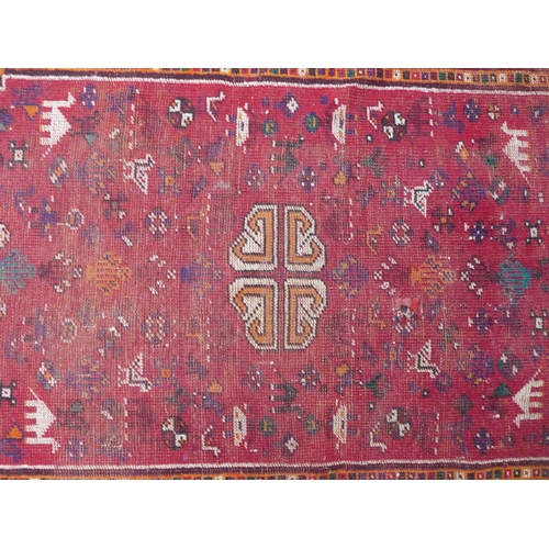 264 - Turkish rug with a worn red field, central hooked medallion with figures and camels,  166 x 112cm.