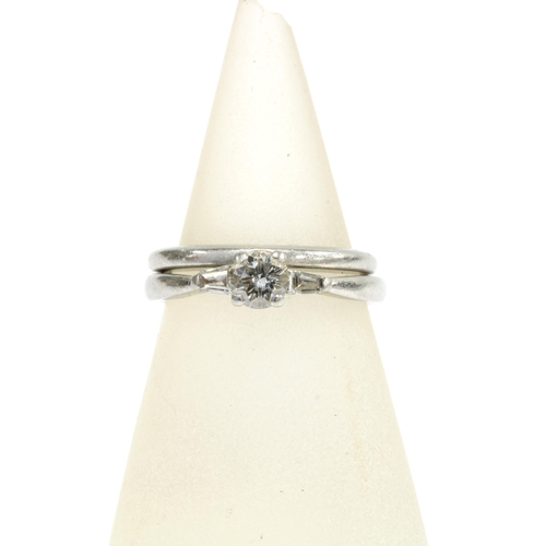 35 - A platinum and diamond ring with a claw set central bright cut diamond flanked by a baguette diamond... 