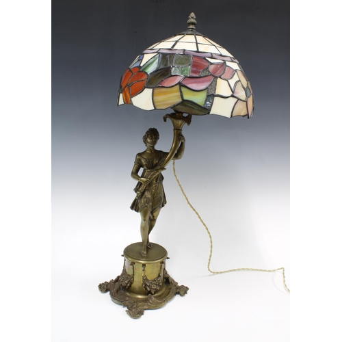 354 - Bronze patinated figural metal table lamp base with a Tiffany style stained glass shade, 65cm