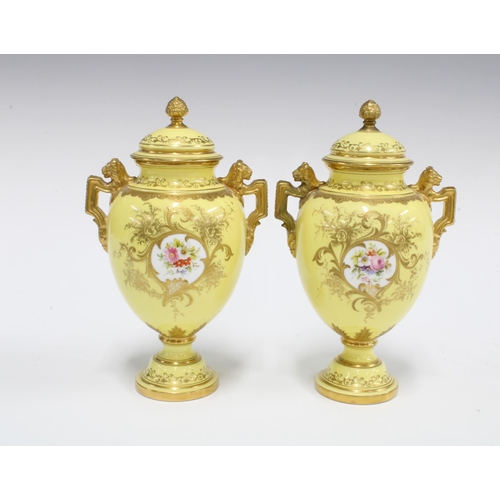 96 - A pair of Coalport twin handled urn vases with covers, yellow ground with handpainted floral panels ... 