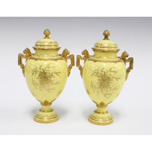 96 - A pair of Coalport twin handled urn vases with covers, yellow ground with handpainted floral panels ... 