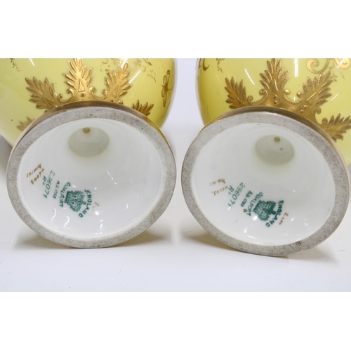 96 - A pair of Coalport twin handled urn vases with covers, yellow ground with handpainted floral panels ... 