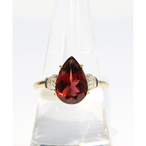 37 - 9ct gold garnet and diamond ring, claw set with a pear cut garnet flanked by three small circular di... 