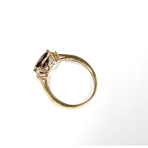 37 - 9ct gold garnet and diamond ring, claw set with a pear cut garnet flanked by three small circular di... 