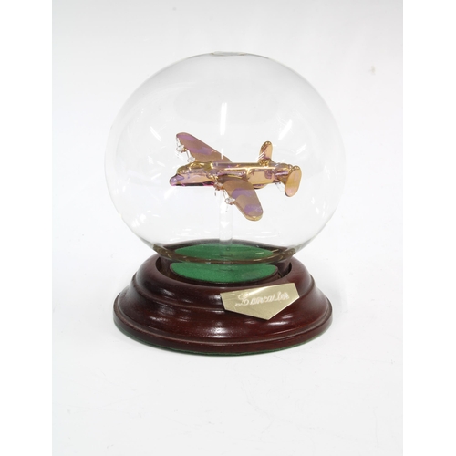 391 - A glass model of a Lancaster Bomber, contained within a clear glass sphere, on a wooden circular bas... 