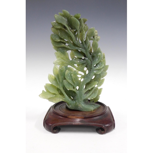 125 - Chinoiserie green jadeite floral carving on a stylised hardwood stand, 21 x 32cm.