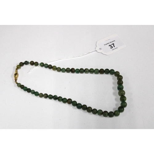 37 - A strand of green jadeite beads with an 18ct gold hand clasp fastening, stamped 18K