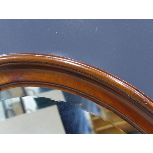 394 - A mahogany wall mirror with an oval bevelled edge plate, 93 x 60cm