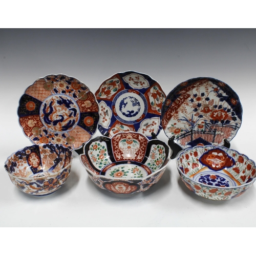 106 - A group of Imari bowls and plates, each typically decorated with chrysanthemums and foliage and with... 