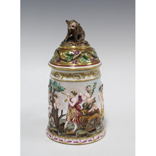 399 - A Capo di Monte tankard decorated in relief with bacchanalian figures, the cover with a boar finial,... 