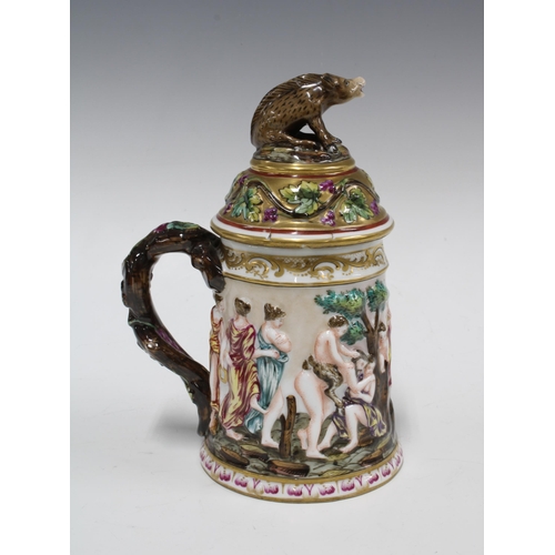 399 - A Capo di Monte tankard decorated in relief with bacchanalian figures, the cover with a boar finial,... 