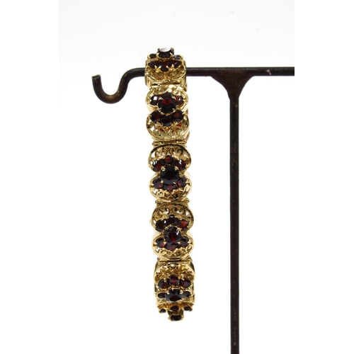 63 - 18ct gold bracelet with eleven panels, each with a group of seven garnets in a flowerhead setting, s... 