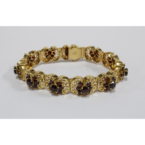 63 - 18ct gold bracelet with eleven panels, each with a group of seven garnets in a flowerhead setting, s... 