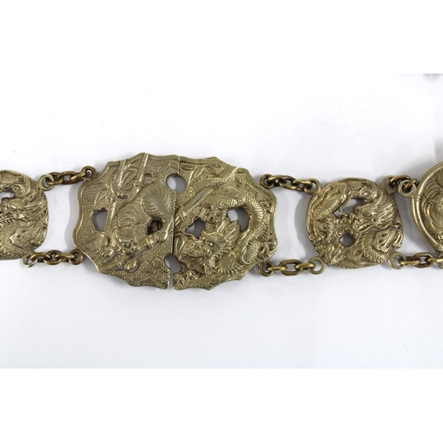 56 - Chinese white metal belt, with thirteen dragon and Buddhistic lion panels with a central two part bu... 