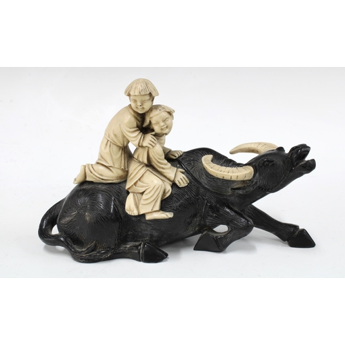 147 - Black resin water buffalo with two faux ivory riders, 23cm.