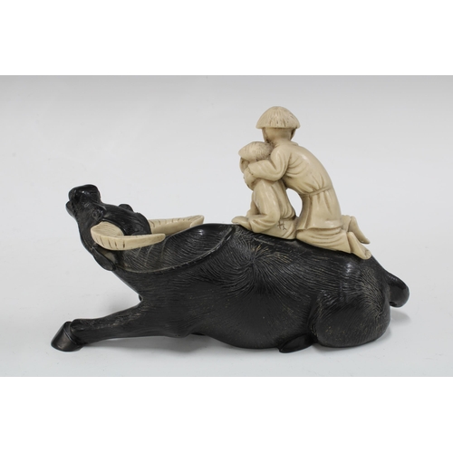 147 - Black resin water buffalo with two faux ivory riders, 23cm.