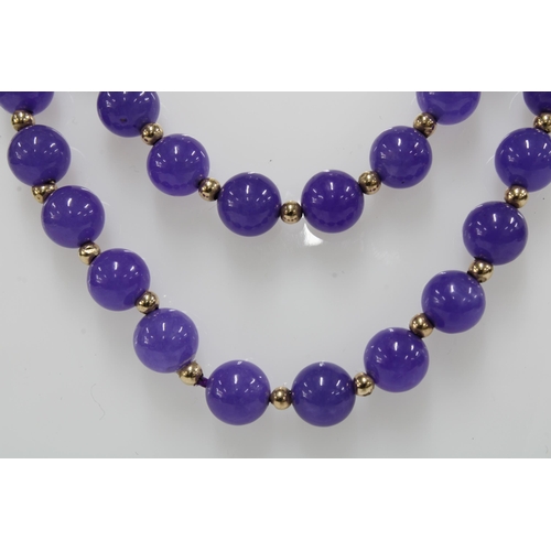 25 - A strand of lilac purple jadeite beads with yellow metal spacers,