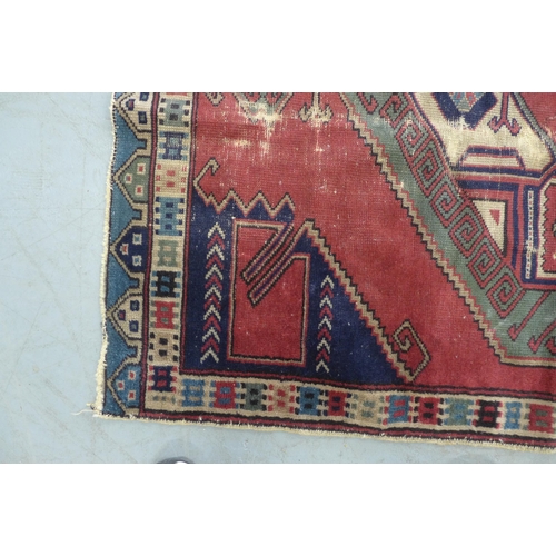 275 - Turkish rug, red field with blue spandrels and central medallion with hooked border, 150 x 114cm.