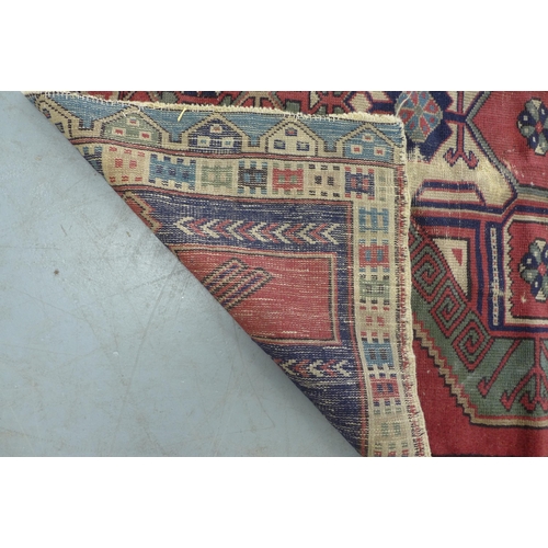 275 - Turkish rug, red field with blue spandrels and central medallion with hooked border, 150 x 114cm.