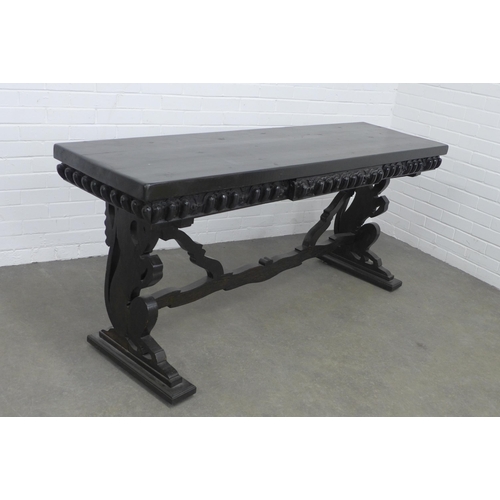 278 - An ebonised wooden table, long rectangular top with a carved frieze, on pierced side supports untied... 