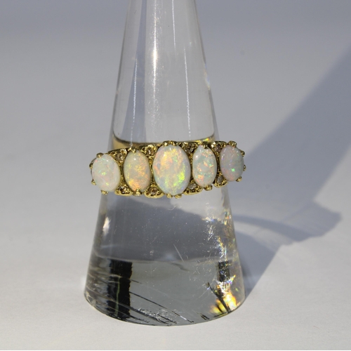 33 - An 18ct gold and opal five stone ring, claw set with graduating opals with eight diamond points in-b... 