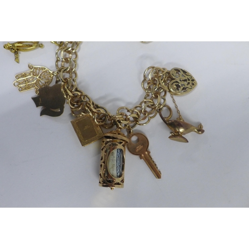 16 - 9ct gold charm bracelet with a quantity of mainly 9ct gold charms, (USA flag not hallmarked and like... 