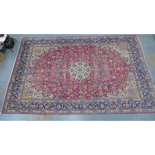 212 - Isfahan carpet, central medallion and red field with scrolling vines, indigo border, 490 x 305cm.