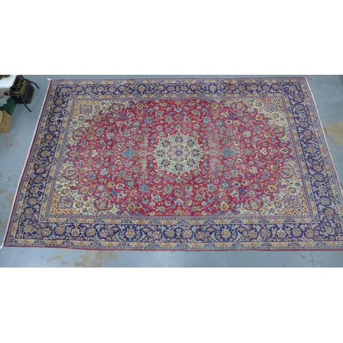 212 - Isfahan carpet, central medallion and red field with scrolling vines, indigo border, 490 x 305cm.