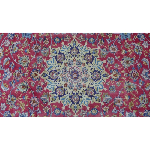 212 - Isfahan carpet, central medallion and red field with scrolling vines, indigo border, 490 x 305cm.