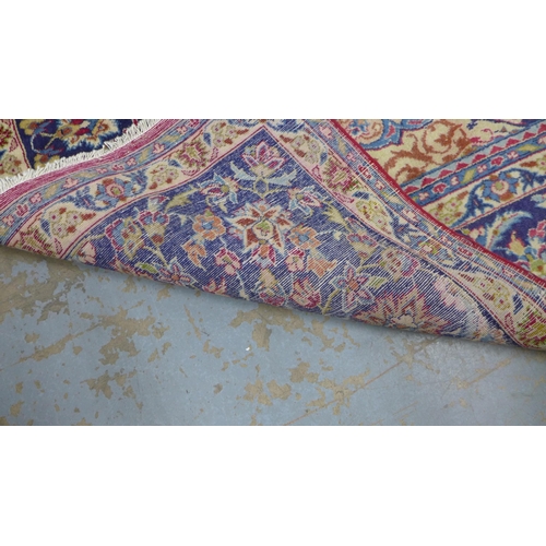 212 - Isfahan carpet, central medallion and red field with scrolling vines, indigo border, 490 x 305cm.